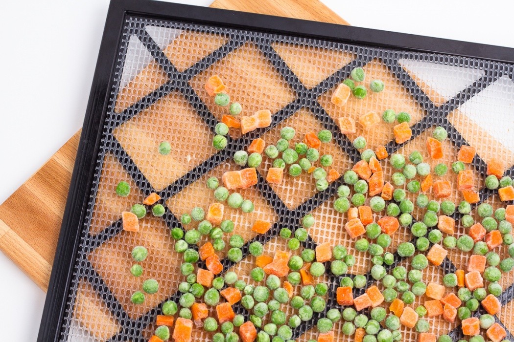 Carefully load the tray because the peas will easily roll off frozen peas and carrots on a dehydrator tray