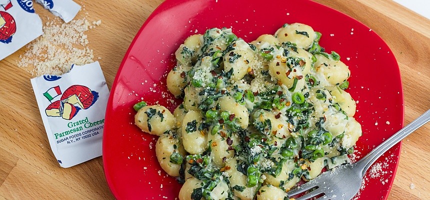 Lemon gnocchi with spinach and peas on a red plate