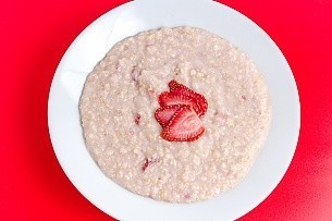 cooked strawberries and cream oatmeal on a red background