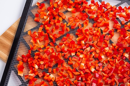 diced red bell peppers spread on a dehydrator tray